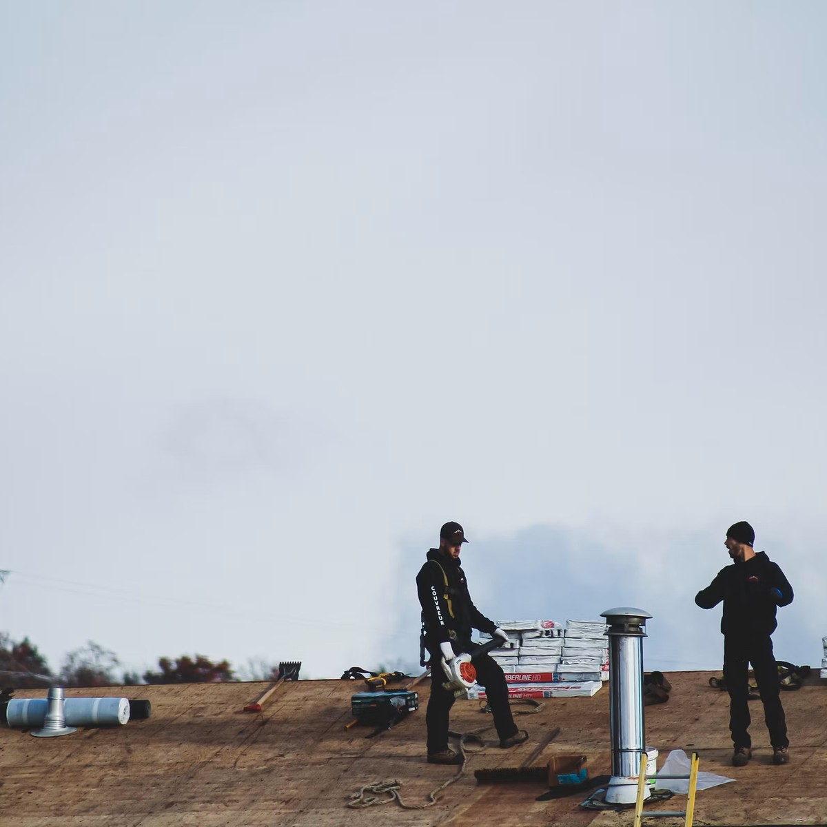 Roofing professionals working on an exposed residential roof with roofing materials ready for installation, representing Roofing Repair services near me.
