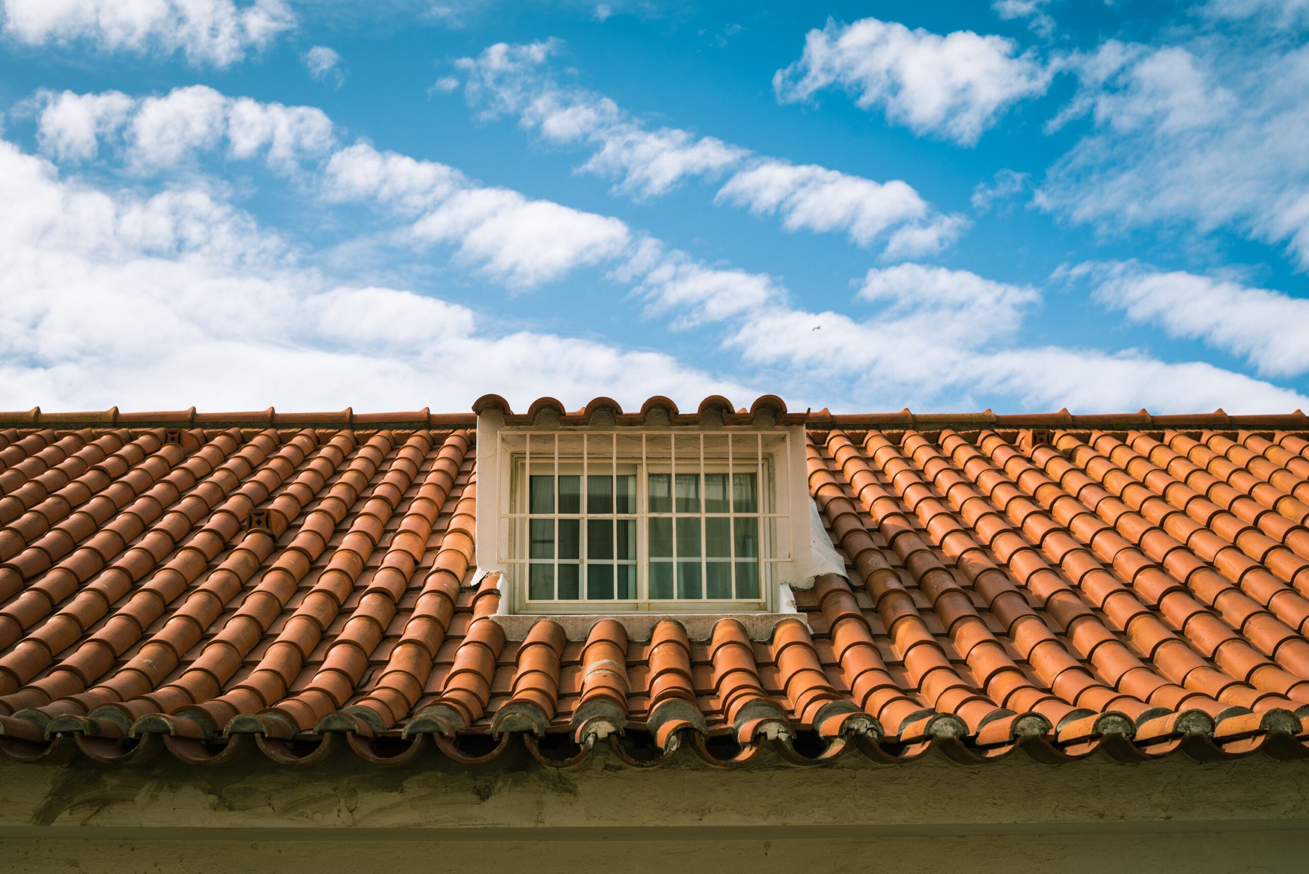 Close-up of a terracotta tiled roof with a skylight window for Reliable Roofing Repair near me