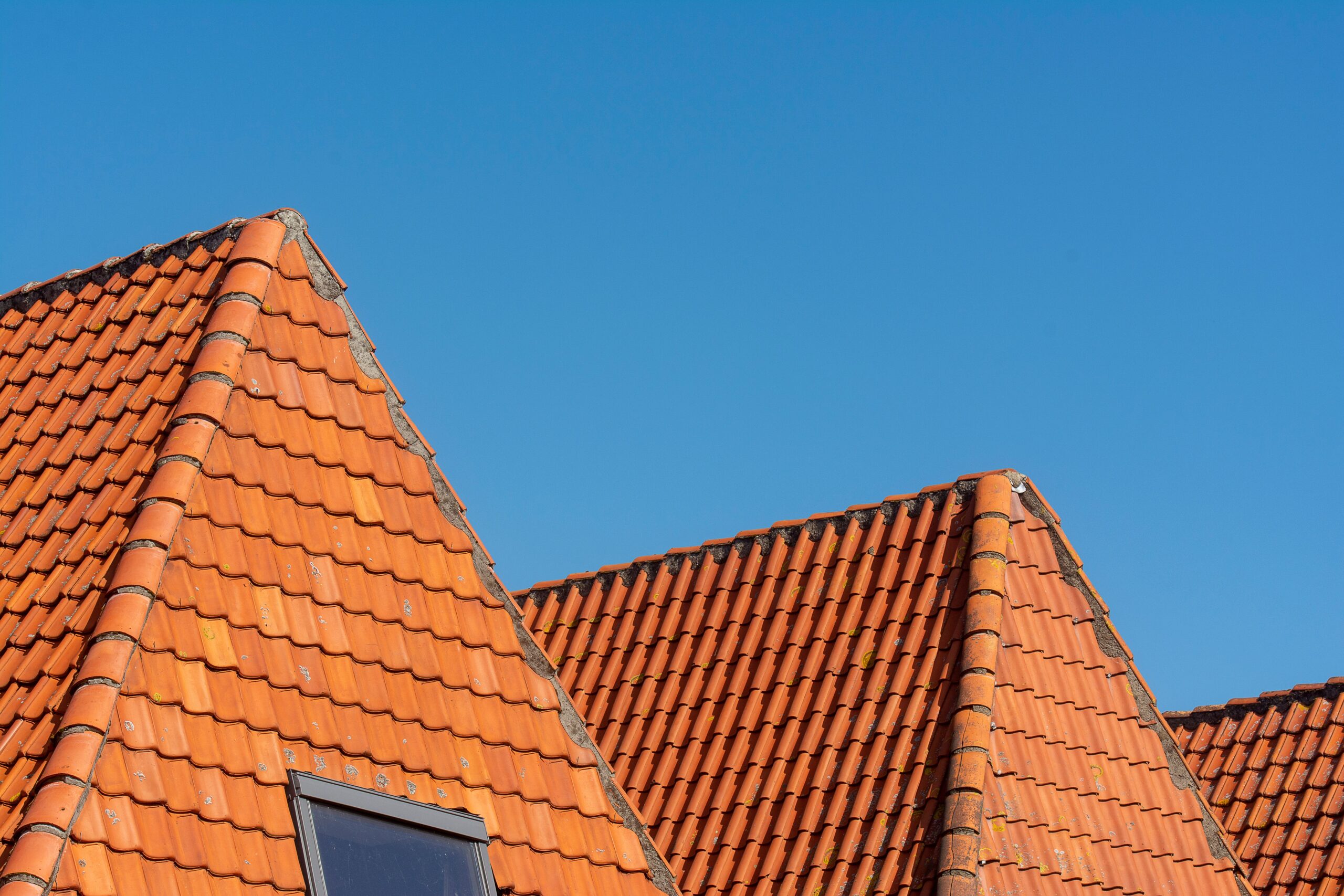 Close-up of red tiled roofs under a clear blue sky, showcasing architectural design for Reliable Roofing Repair in Greeley, CO