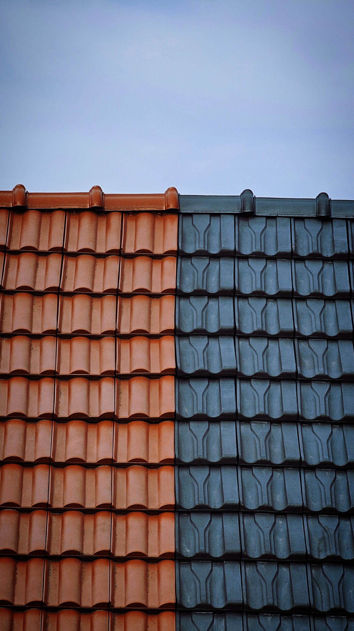 Detailed view of contrasting red and blue tiled rooftops under a clear sky for Professional Roofing Repair in Evans, CO